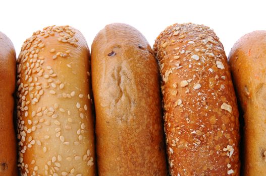 A closeup of 5 bagels standing on their sides with a white background. Bagels include, sesame seed, cinnamon raisin, mulit grain, and blueberry.