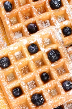 High angle shot of blueberry waffles. Closeup of waffles covered with powdered sugar and fresh blueberries.