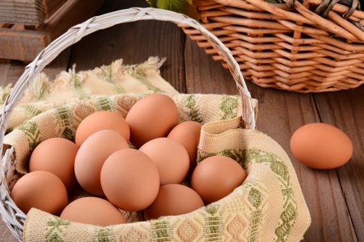 Closeup of a basket full of brown eggs in a rustic farmhouse like setting. Horizontal format with shallow depth of field.