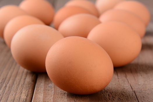 Closeup of a group of brown eggs on a rustic wooden table. Horizontal format with shallow depth of field.
