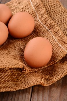 Closeup of 4 brown eggs on a burlap sack.  Vertical format with shallow depth of field.