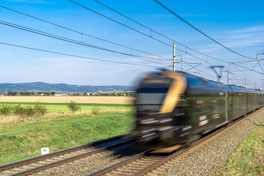 an electric train passes through a beautiful landscape on railway tracks.