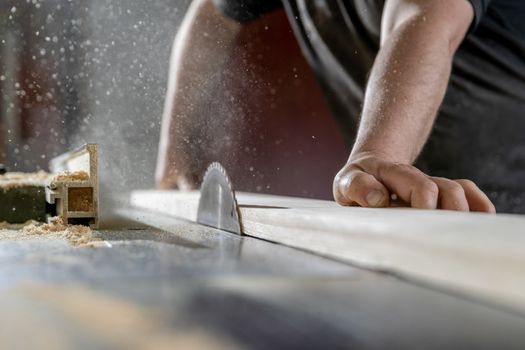 A man cuts wood on a circular saw in a joinery.