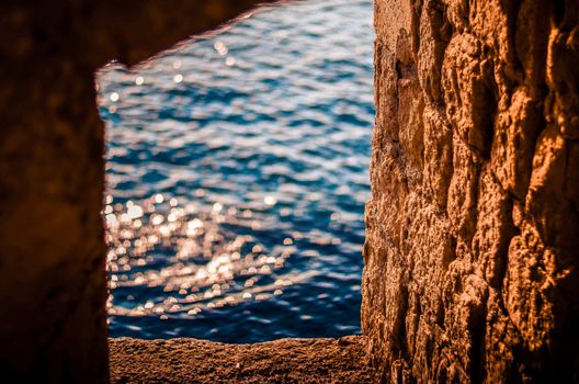 Castle ruins. Window in the old stone wall. Reflection of the sun's rays in the sea water