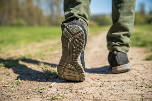 a tourist walks on a dirt road. close up of legs and shoes.