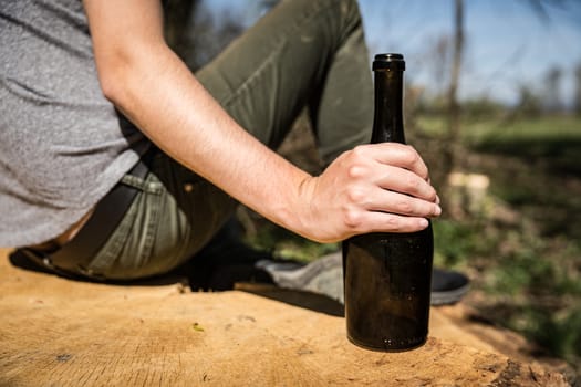 a bottle of wine in a man's hand, drinking alcohol in nature.