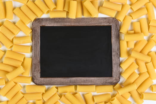 Chalkboard surrounded by rigatoni pasta. Top vies filling the frame.