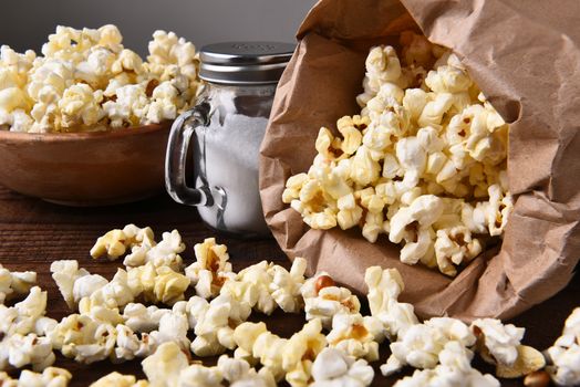 Closeup of a bag of fresh popped popcorn with a bow and salt shaker.