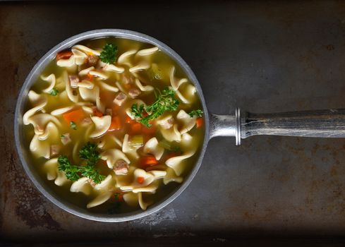 Top view of a pot of fresh homemade, Chicken Noodle Soup. Horizontal format with copy space. Can be rotated - works as a vertical as well.