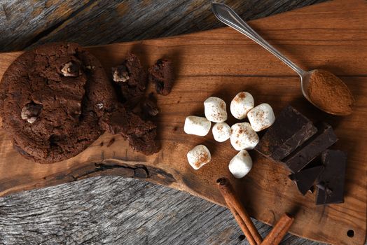 Overhead shot of a cutting board with chocolate chunks cinnamon sticks and cookies. 