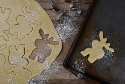 Top view of a baking sheet with a moose shaped cookie, with dough and additional moose shapes in raw dough.