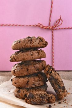 Closeup of a stack of chocolate chocolate chip cookies in front of a pink bakery box.