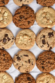 A group of assorted cookies. Chocolate chip, oatmeal raisin, white chocolate fill the frame.
