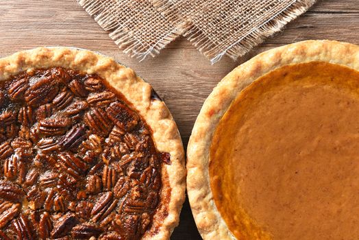 Closeup of two pies on a Thanksgiving holiday table. Pumpkin and pecan pies are traditional desserts for the American holiday.