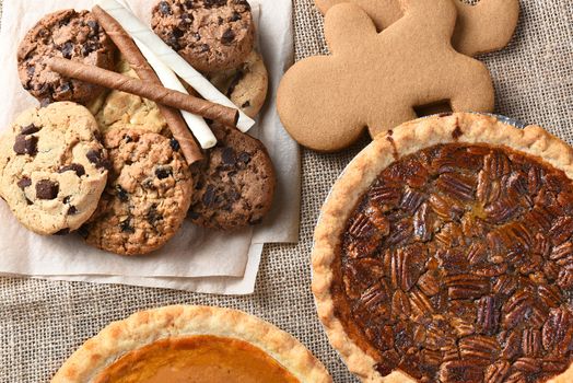 Assorted holiday desserts including:  gingerbread, pumpkin pie, pecan pie, chocolate chip and oatmeal raisin cookies, 