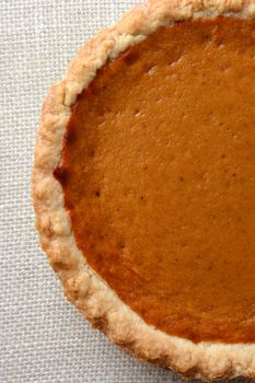 High angle shot of a Thanksgiving Pumpkin Pie.  Pumpkin pie is a traditional desert served on the American Holiday. Vertical format, only half the fie filling the frame.