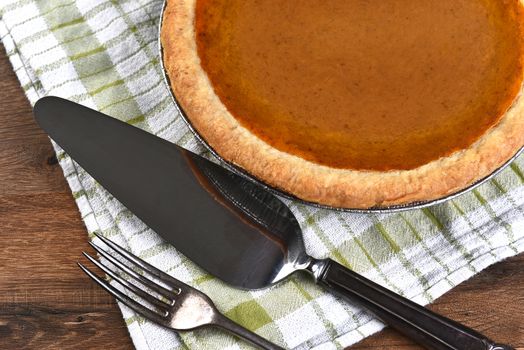 High angle view of a pumpkin pie, server and fork. The dessert is part of a typical Thanksgiving Day Feast.