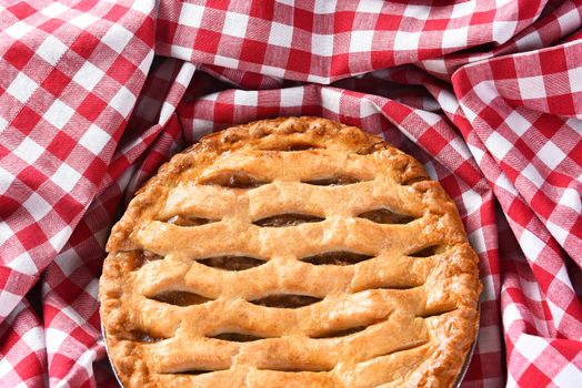 Closeup of a fresh baked Apple Pie surrounded by a red and white checked table cloth. 