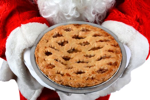 Closeup of Santa Claus holding a fresh baked apple pie in front of his torso. The man is unrecognizable. Horizontal format on a white background.