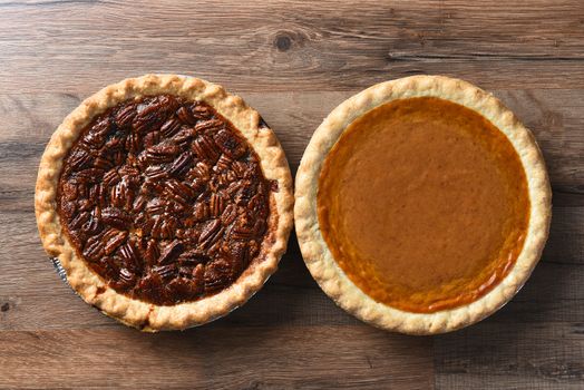 Top View of a fresh baked pumpkin pie and a pecan pie on a rustic wood table, for Thanksgiving feast.