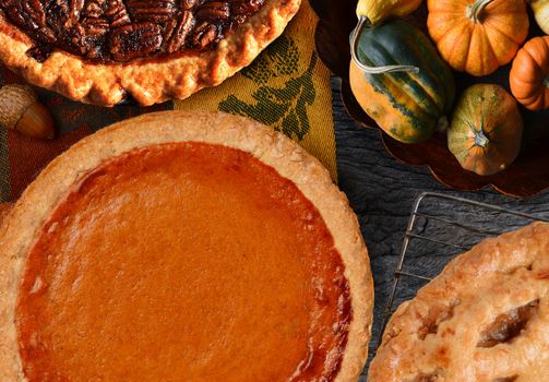 Pumpkin, Pecan and Apple Pies for Thanksgiving with a bowl of decorative gourds.