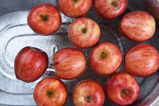 High angle horizontal shot of a metal tub filled with water and apples for the Halloween custom of Apple Bobbing.