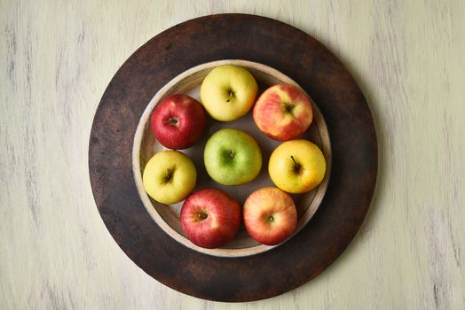 High angle view of a bowl of assorted apples on a rustic table.