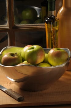 Bowl of Apples on rustic table top in front of window with strong side light vertical composition