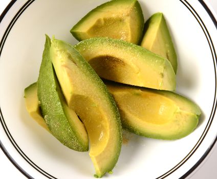 Closeup of avocado slices sprinkled with seasonings ready to be made into guacamole.