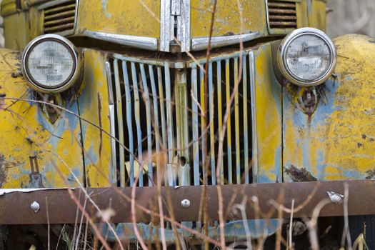 An old abandoned car sits in a field as it rusts away
