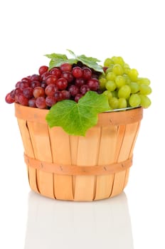A wicker basket full of Red and Green Grapes. Vertical format on a white background with reflection.