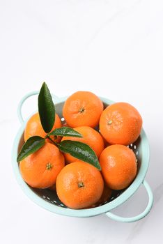 High angle view of a colander filled with fresh picked mandarin oranges.