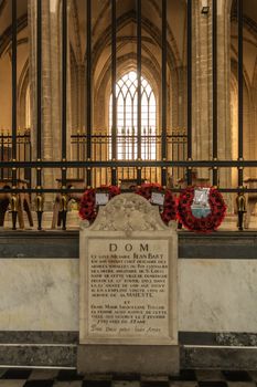 Dunkerque, France - September 16, 2018: Inside Saint Eloi Church in Dunkirk. Tombstone of Jean Bart and his wife. Red poppy wreaths, brown stone church wall with window as background.