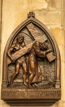 Dunkerque, France - September 16, 2018: Inside Saint Eloi Church in Dunkirk. closeup of fifth Station of the cross wherein Simon of Cyrene helps carry the cross. Only shades of brown.