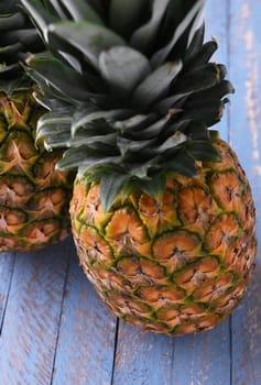 High angle shot of two fresh ripe pineapples on rustic wooden blue table.