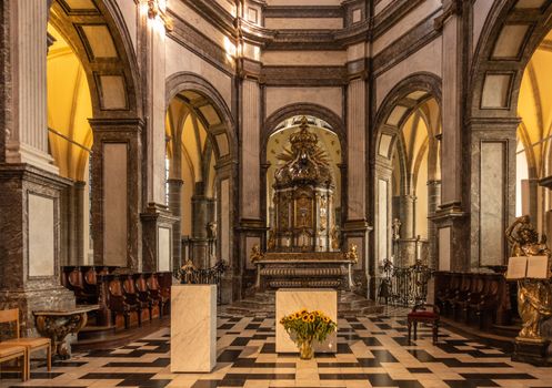 Kortrijk, Flanders, Belgium - September 17, 2018: Chancel and main altar in Notre Dame Church offers shades of brown, yellow and beige. Flowers, arches, tabernacle, altar.