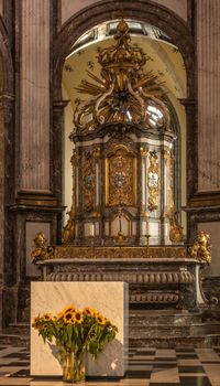 Kortrijk, Flanders, Belgium - September 17, 2018: Main altar in Notre Dame Church offers shades of brown, yellow and beige. Flowers, arches, tabernacle, altar.