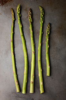 Five Asparagus Spears on a metal cooking sheet. Vertical format.