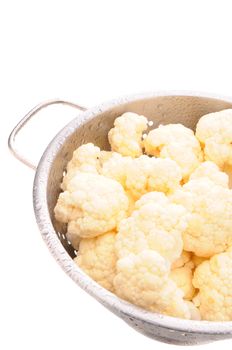 Closeup of cauliflower florets misted with water in a metal colander. Vertical Format isolated on white.