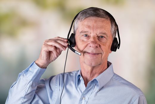 Senior caucasian man using headset to talk to customers or team in work from home.