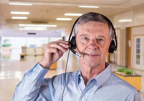 Senior caucasian man using headset to talk to customers or team in office environment