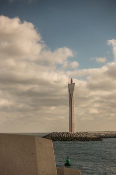 Oostende, Flanders, Belgium - September 18, 2018: 21st century light tower to guide ships into harbor is tall modern structure with radar equipment. White cloudy sky. North Sea water.