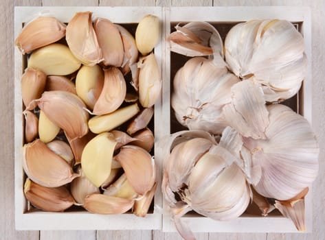 High angle view of garlic bulbs and cloves in small white wood crates. 