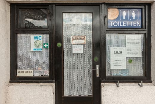 Oostende, Flanders, Belgium - September 18, 2018: Closed restroom facilites on boardwalk near fishermen landing point charge money for every discharge. Windows in black frame against white wall.