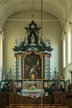 Brugge, Flanders, Belgium - September 19, 2018: Main altar dedicated to Saint Elizabeth with calvary painting in church of Ten Wijngaarde Beguinage of Bruges. Secluded chancel, sculptures and light falls in through windows.