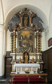 Brugge, Flanders, Belgium - September 19, 2018: Side altar dedicated to Madonna in church of Ten Wijngaarde Beguinage of Bruges. Painting for three saints, sculptures.