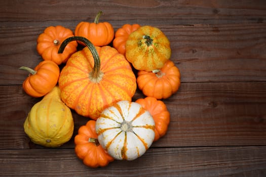 High angle shot of a pile of decorative pumpkins and gourds on a rustic dark wood table. Horizontal format with copy space.