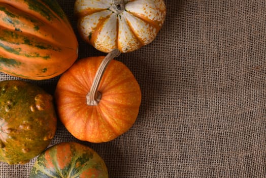 Decorative gourds and pumpkins on a burlap surface with copy space.