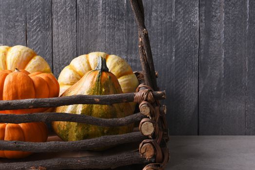 Decorative gourds and pumpkins in a rustic twig basket. Closeup in horizontal format with copy space.