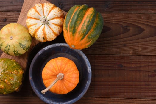 High angle shot of a group of ornamental pumpkins and gourds on a rustic wood table.